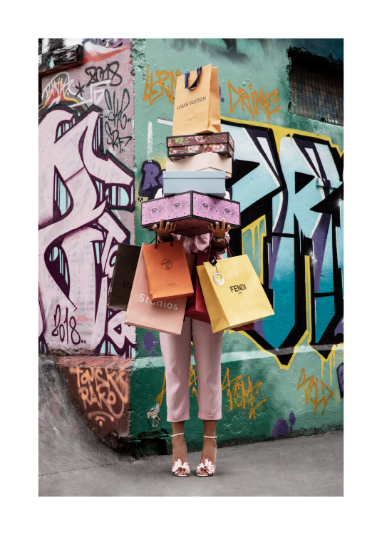  – Fotografía de una mujer frente a una pared pintada con grafitis que sostiene muchas bolsas y cajas de compra