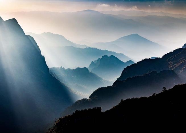 – Fotografía de montañas y rayos de sol colándose por la niebla. 