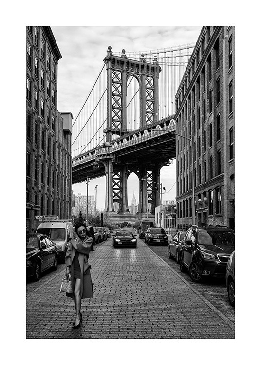  – Fotografía en blanco y negro de una mujer que lleva una gabardina por las calles de Nueva York y el puente de Manhattan de fondo