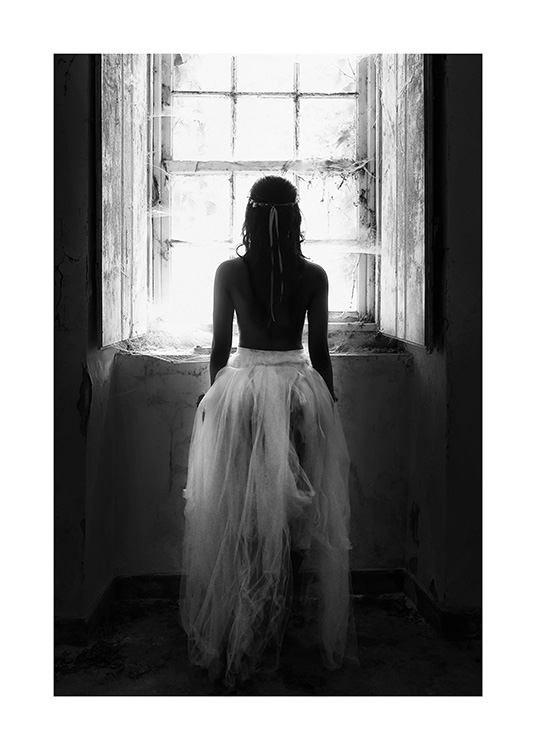 Fotografía en blanco y negro de una mujer de pie delante de una ventana con una falda de tul