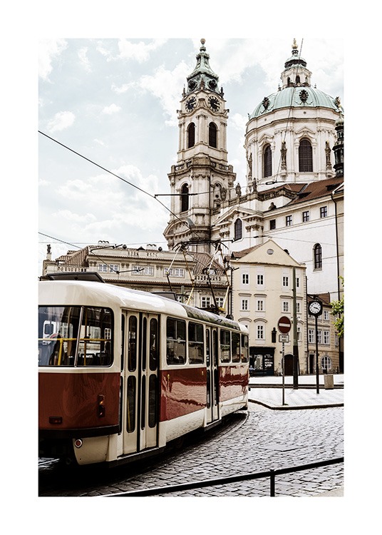  - Fotografía tomada en Praga de un tranvía colorado frente a una iglesia blanca. 