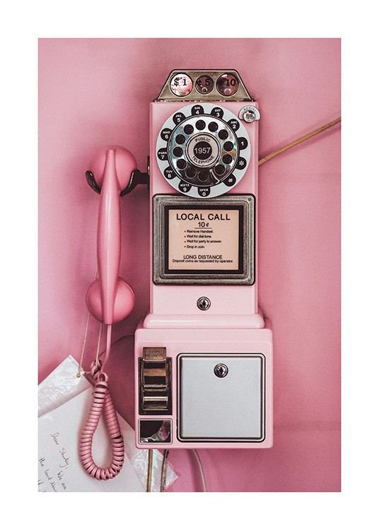 - Fotografía de un teléfono público antiguo en color rosa y fondo rosa.