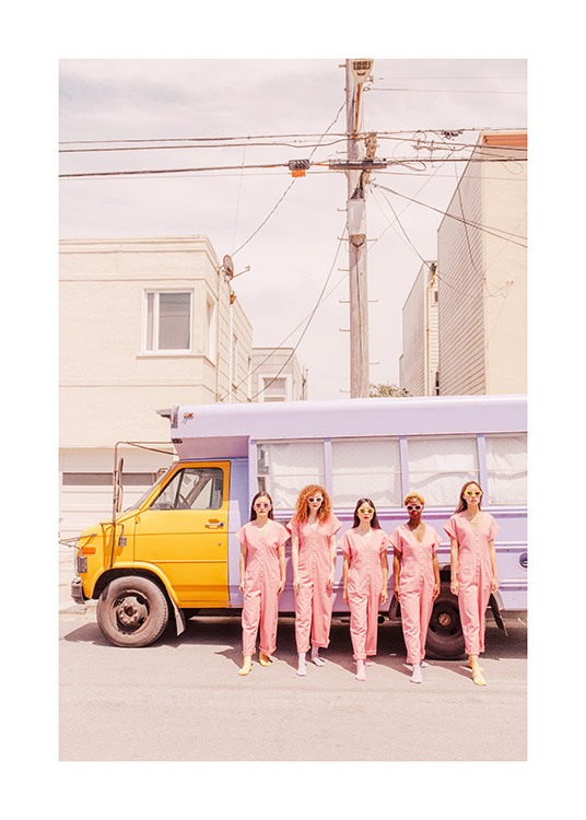  - Fotografía de cinco mujeres en monos rosa y con gafas de sol frente a un camión color amarillo púrpura. 