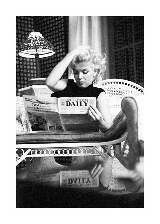  – Fotografía en blanco y negro con la imagen de Marilyn Monroe sentada en un sofá leyendo el periódico