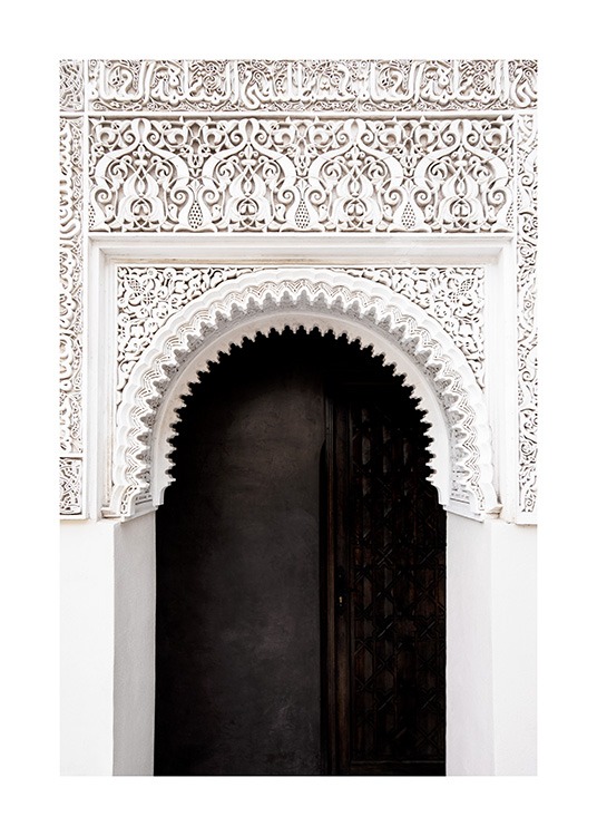  - Fotografía de un arco ovalado blanco con detalles y parones artesanales y una puerta negra.