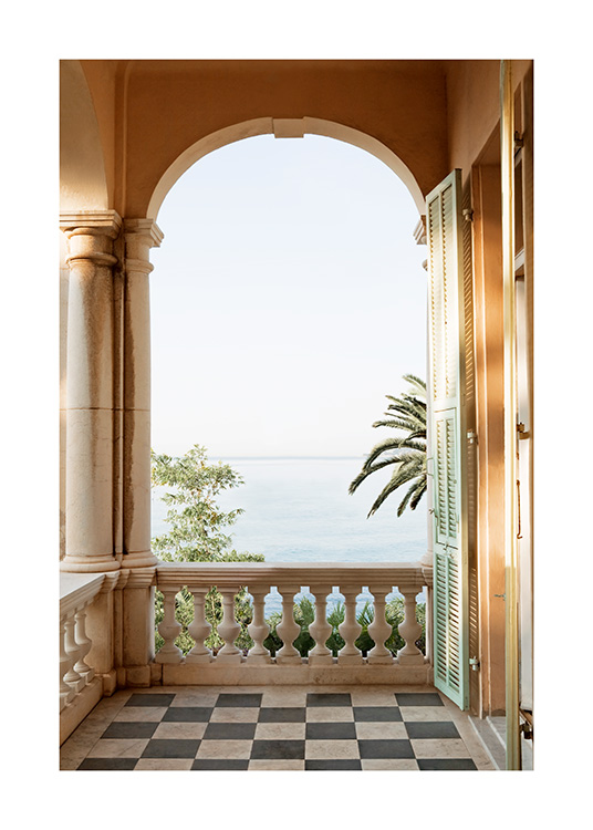  – Fotografía de un balcón con piso cuadriculado y una columna con arco que da a un paisaje con mar y palmeras