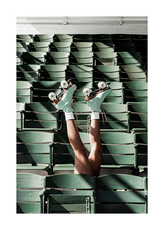  – Fotografía de dos piernas con patines en un estadio con asientos de color verde