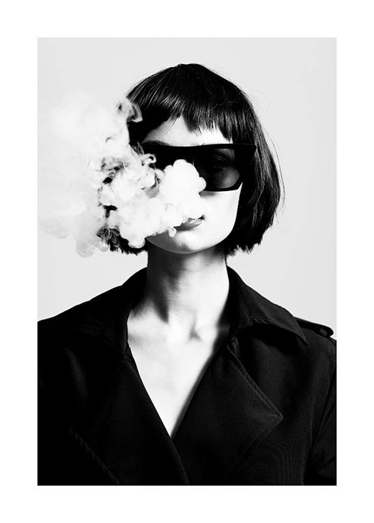  – Fotografía en blanco y negro de una mujer que lleva un trench negro y gafas de sol negras, y tiene humo de cigarrillo saliéndole por la boca.