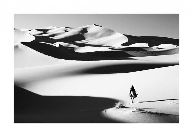  – Fotografía en blanco y negro de un desierto y una mujer caminando por las dunas.