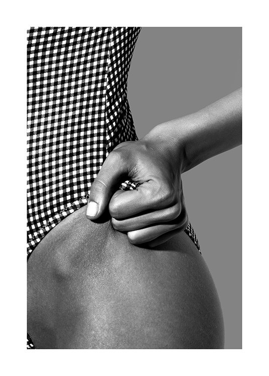  – Fotografía en blanco y negro de una mujer en traje de baño a cuadros con una mano en la cadera que coge el borde de la prenda.