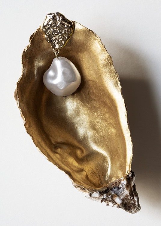  – Fotografía de una concha dorada en su interior con un pendiente de perlas dorado dentro.