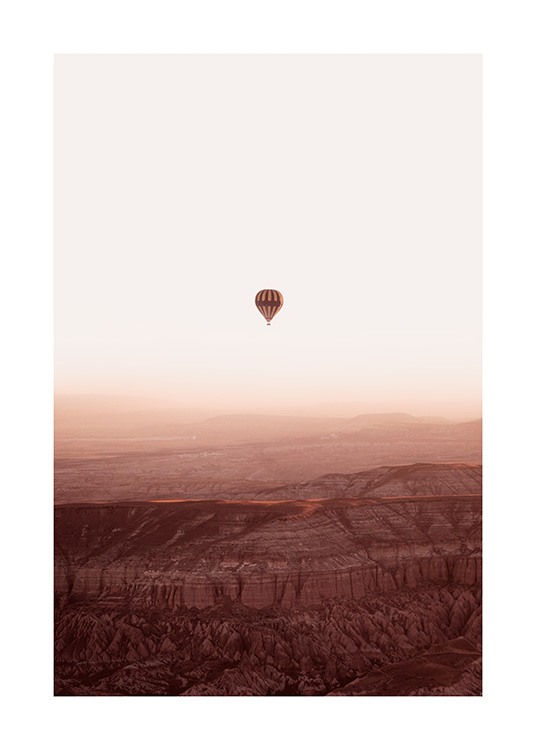  – Fotografía de un paisaje montañoso con un globo aerostático que surca el cielo de la imagen.