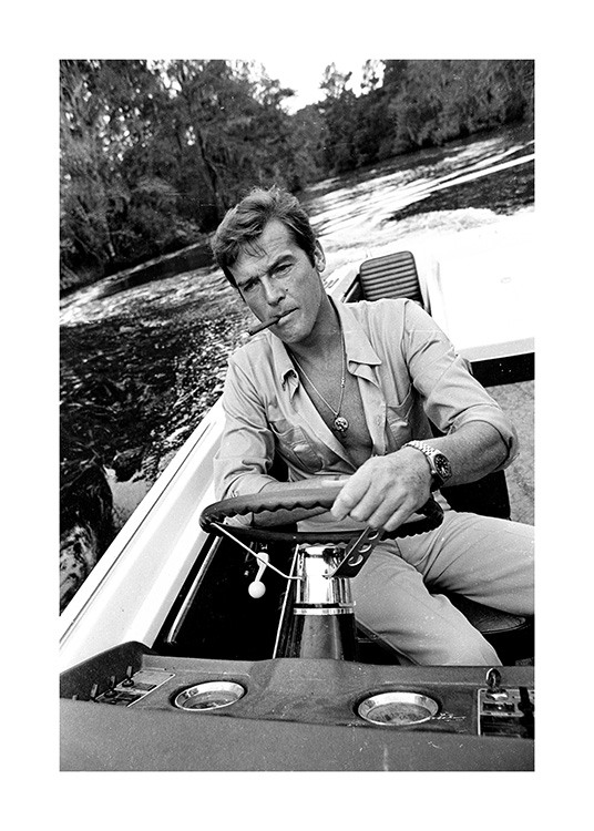  – Fotografía en blanco y negro del actor Roger Moore con un cigarro en la boca a bordo de una embarcación.