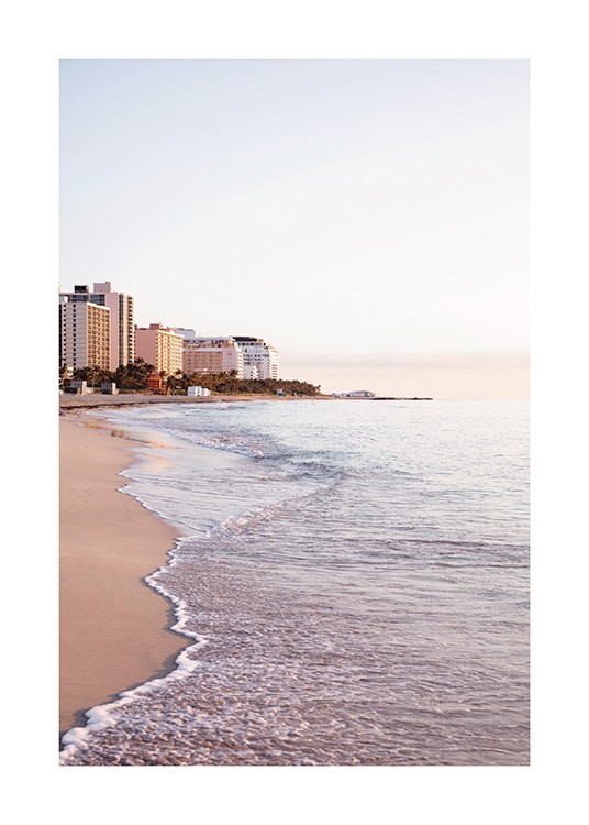  – Fotografía de una playa en el atardecer de Miami con olas serenas que abrazan la costa y edificios al fondo de la imagen.