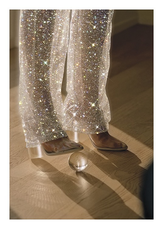  – Fotografía de los pantalones brillantes de una mujer con botas y una bola de cristal debajo de uno de sus zapatos.