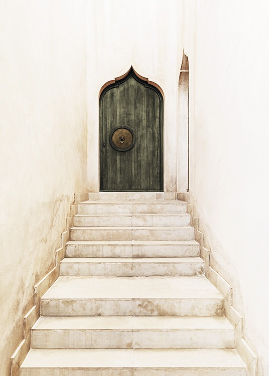  – Fotografía de una escalera y paredes de mármol en color beis con una puerta verde en el medio de la imagen.