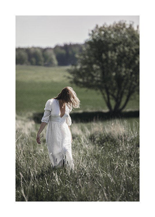  – Fotografía de una mujer con vestido blanco en un campo de pastos altos, y con árboles detrás.