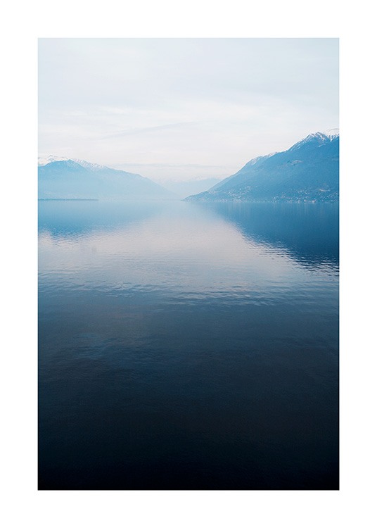  – Fotografía de un lago de agua serena con montañas al fondo y neblina