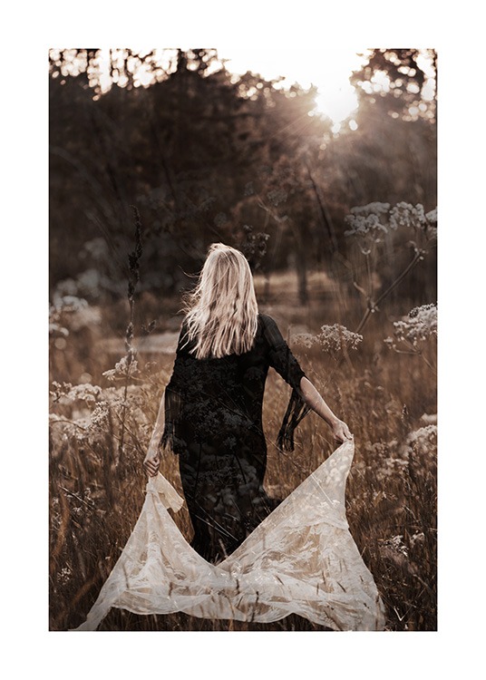  – Fotografía de una mujer con vestido negro caminando por el campo con una tela de encaje en la mano