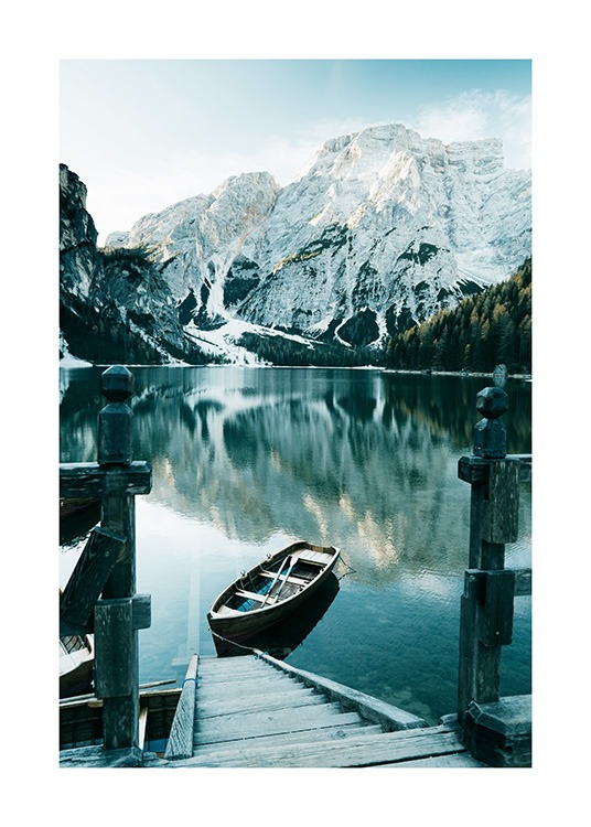  – Fotografía de un paisaje con montañas nevadas, árboles y un bote en un pequeño embarcadero en primer plano