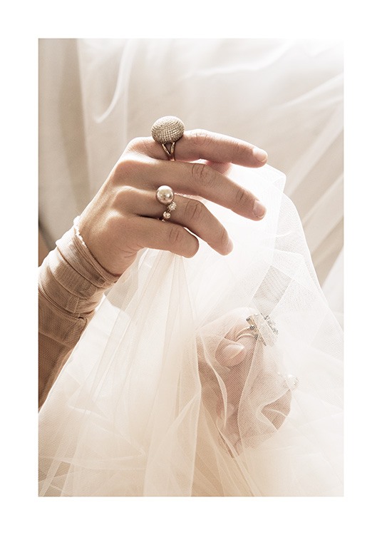  – Fotografía de las manos de una mujer con anillos en los dedos y una tela de tul blanca