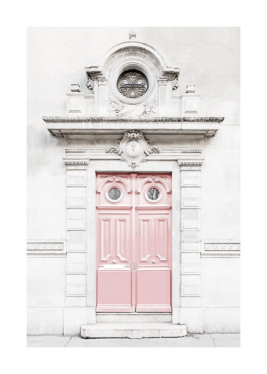  – Fotografía de una puerta rosa en la facha de un edificio gris claro que tiene detalles barrocos
