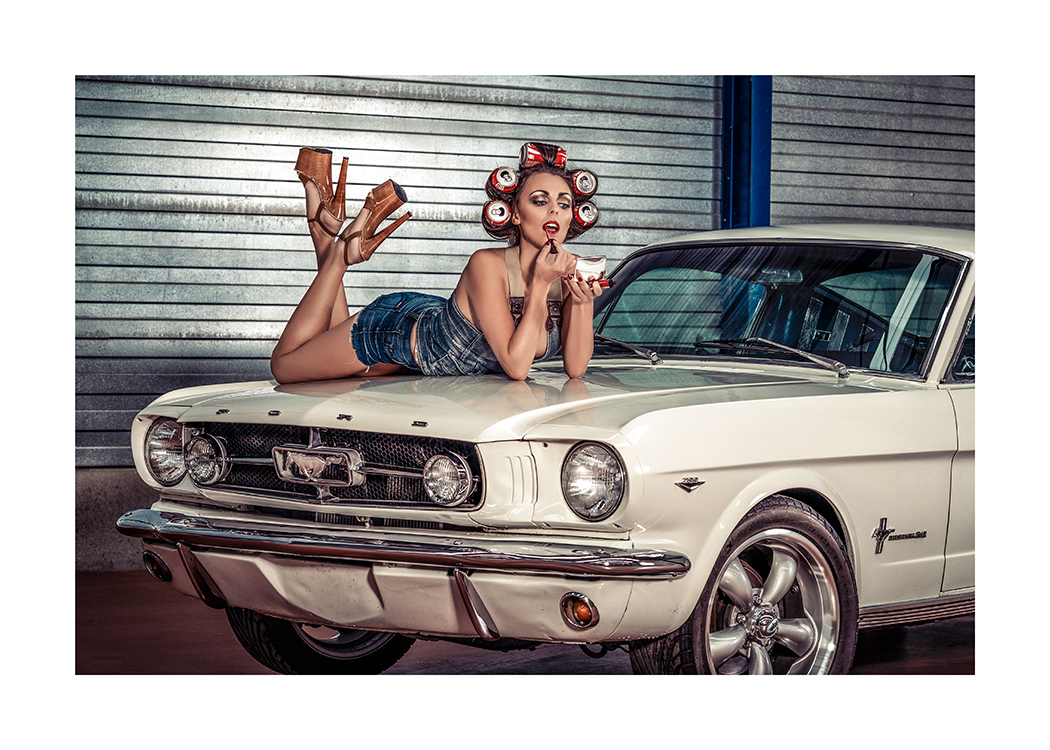  – Fotografía de una mujer latas de refrescos en el pelo pintándose los labios sobre el capó de un coche antiguo