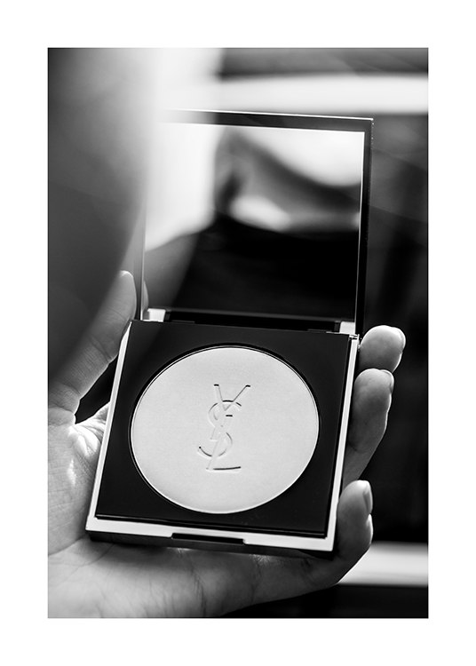  – Fotografía en blanco y negro de un polvo de maquillaje compacto con un espejo de la marca YSL