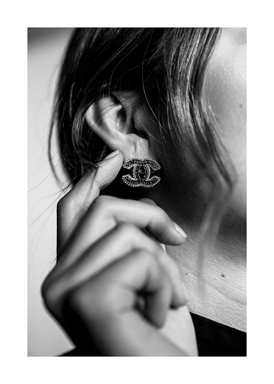  – Fotografía en blanco y negro de una mujer tocándose un pendiende brillante con el logo de Chanel