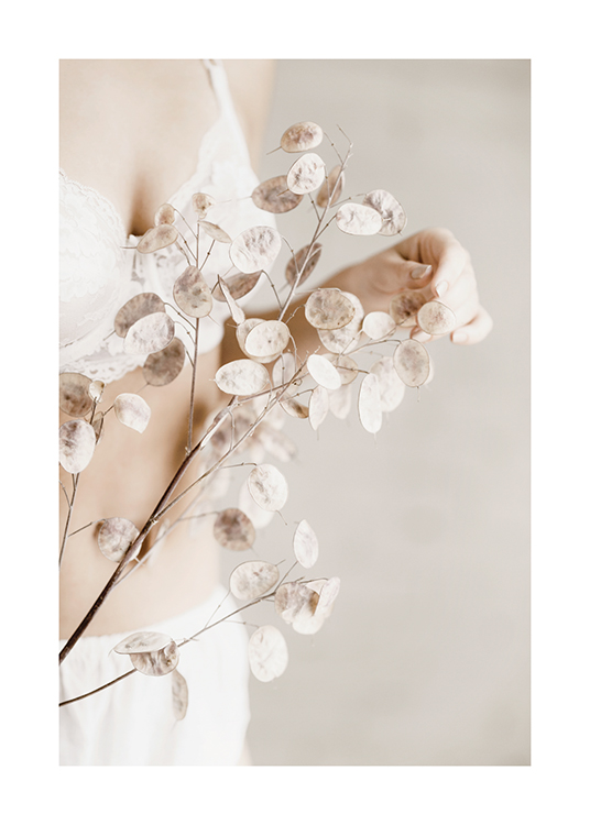  – Fotografía de una mujer con una rama con flores blancas disecadas en la mano.