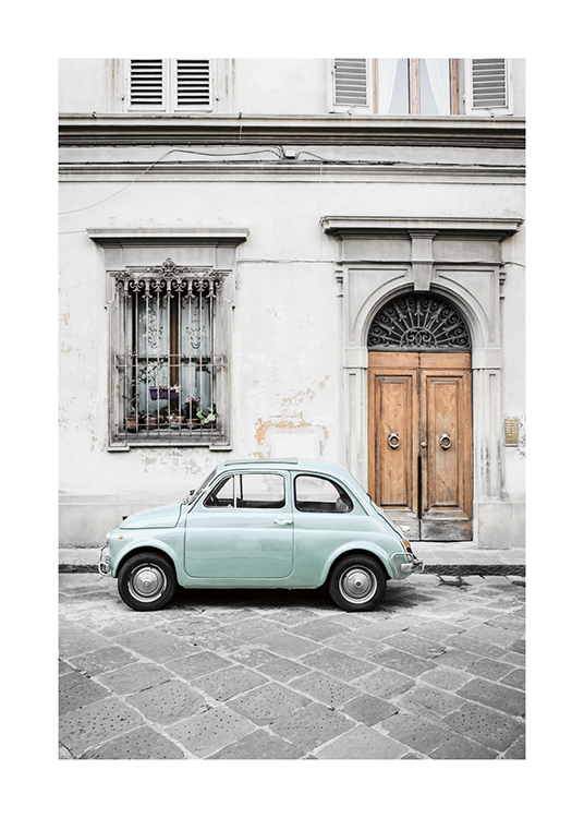  – Fotografía de un coche antiguo color verde menta estacionado fuera de un edificio viejo y gris.
