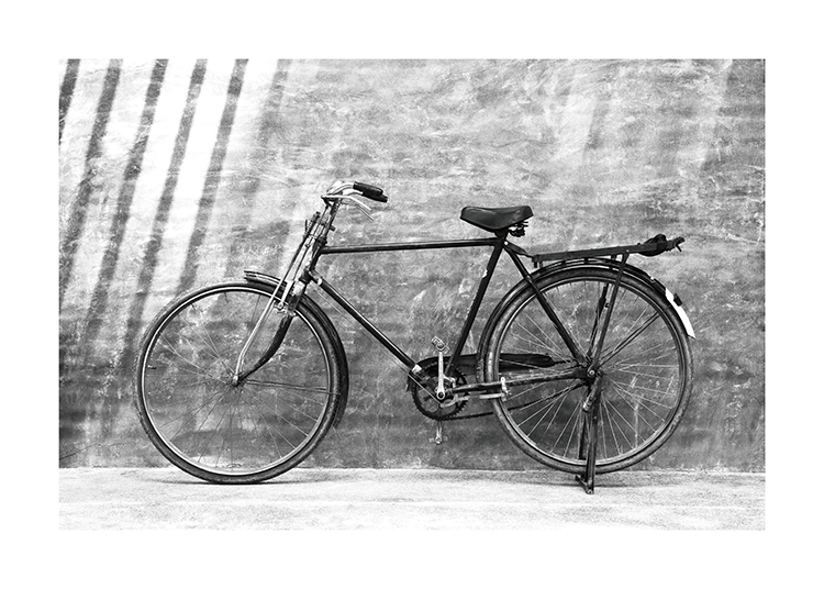  – Fotografía en blanco y negro de una bicicleta antigua apoyada contra una pared.