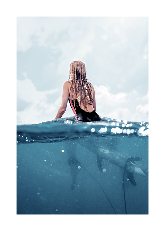  – Fotografía de una mujer vista de espaldas sentada en una tabla de surf en el mar