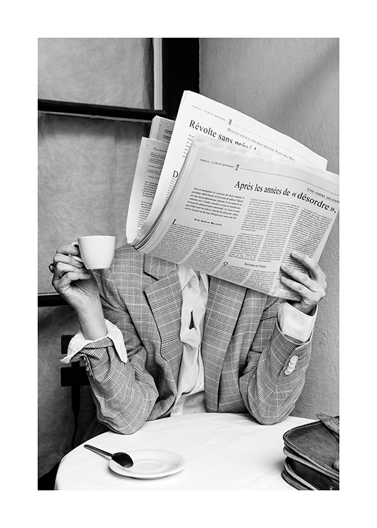  – Fotografía en blanco y negro de una persona sentada en una cafetería leyendo un periódico que le tapa el rostro