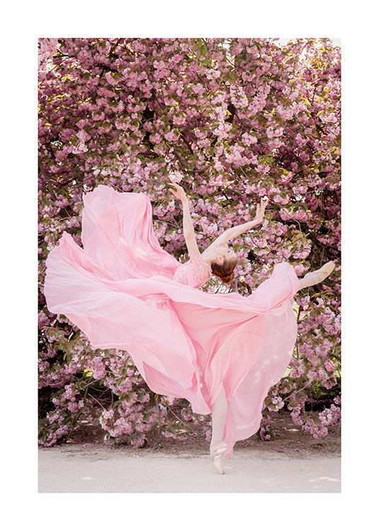  – Fotografía de una bailarina de ballet en pose de baile con vestido rosa y una pared de flores de fondo