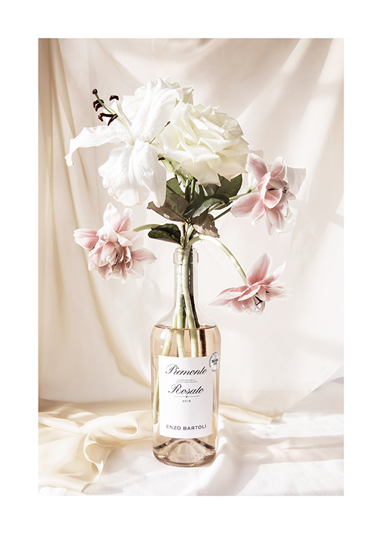  – Fotografía de un ramo de flores rosas y blancas en una botella de vino rosado