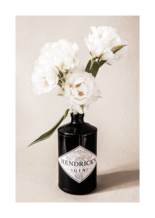  – Fotografía de una botella negra de ginebra con flores blancas dentro y fondo beis claro de aspecto granulado