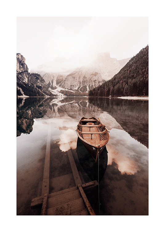  – Fotografía de un lago de agua serena con una embarcación pequeña de madera en primer plano y montañas nevadas de fondo