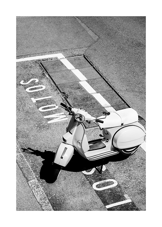  – Fotografía en blanco y negro de una motoneta antigua estacionada en un estacionamiento que tiene palabras escritas en blanco en el asfalto