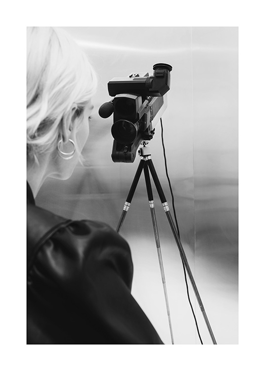  – Fotografía en blanco y negro de una mujer rubia detrás de una videocámara